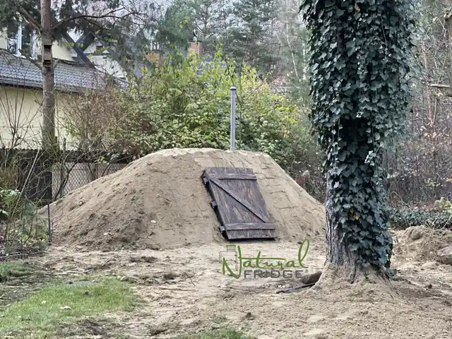 Zatrávnený kopec nad pivnicou s dvierkami, po zásype